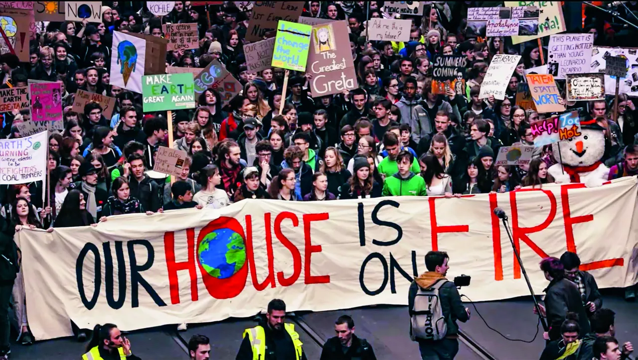 &Uuml;ber 100 Menschen demonstrieren mit Schildern und Plakaten auf den Stra&szlig;en f&uuml;r eine gerechte und dringende Klimapolitik.