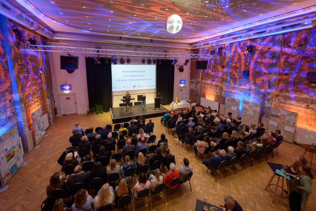 Ein gut besuchtes Theater. Auf der Bühne spielt eine Band