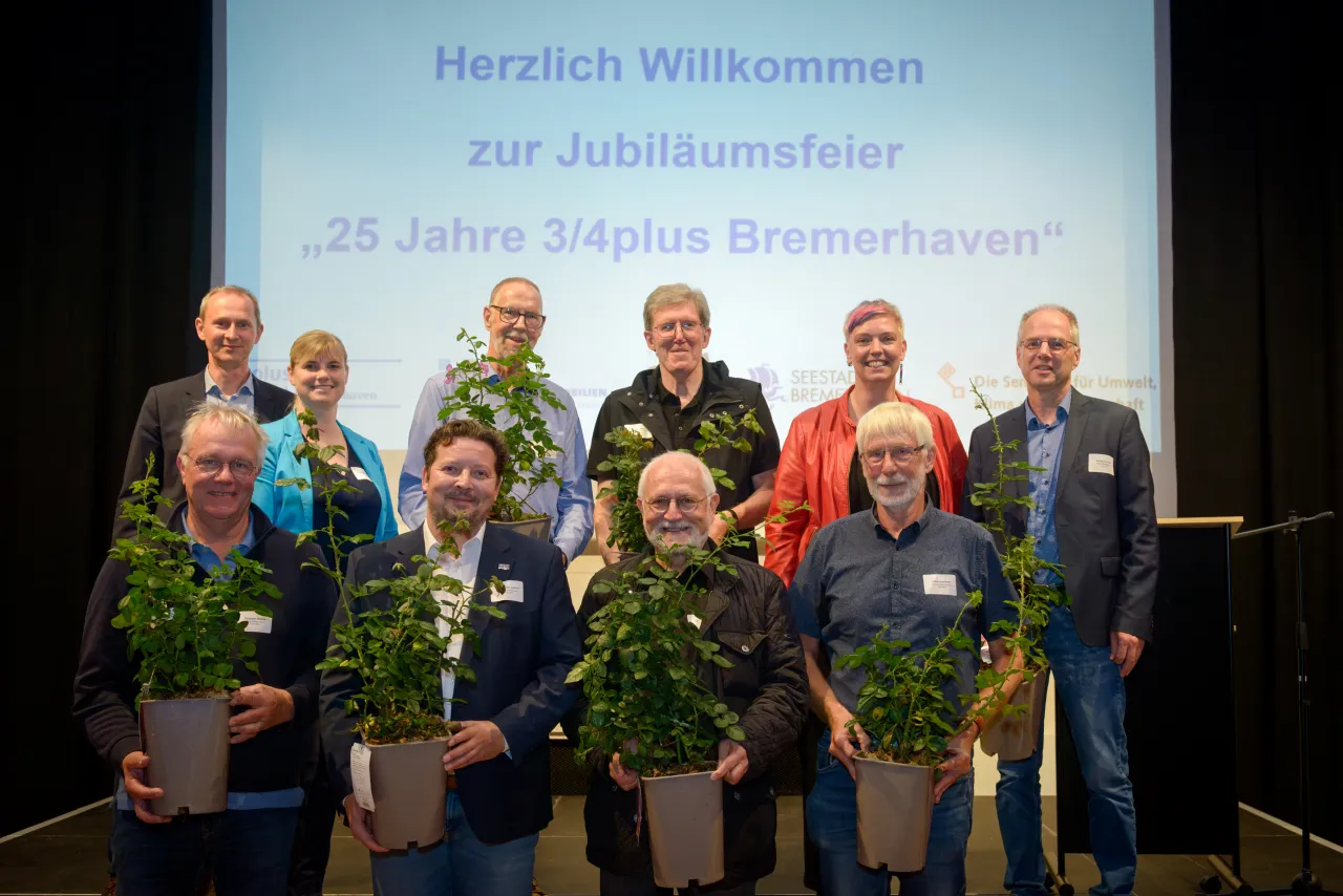 Eine Gruppe Menschen mit Pflanzen in der Hand auf einer Bühne.