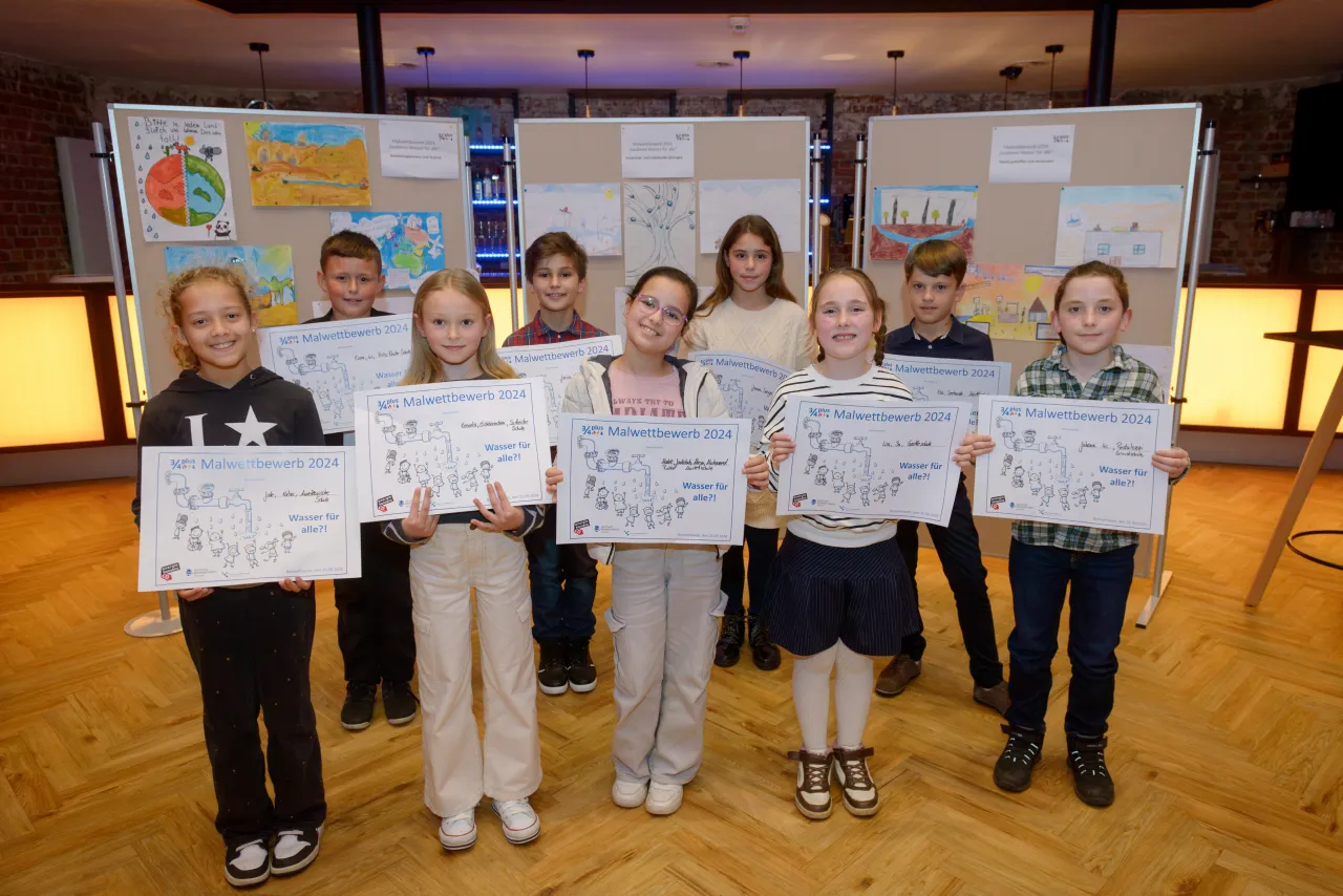 Einige Kinder mit Urkunden vor Stellwänden mit ihren gemalten Bildern.