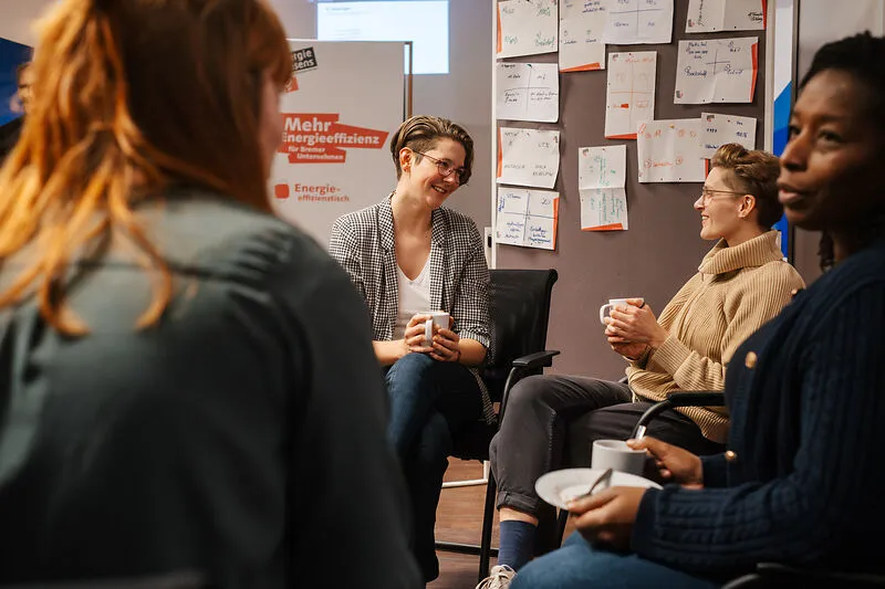 Frauen sitzen in einem Halbkreis und tauschen sich aus.