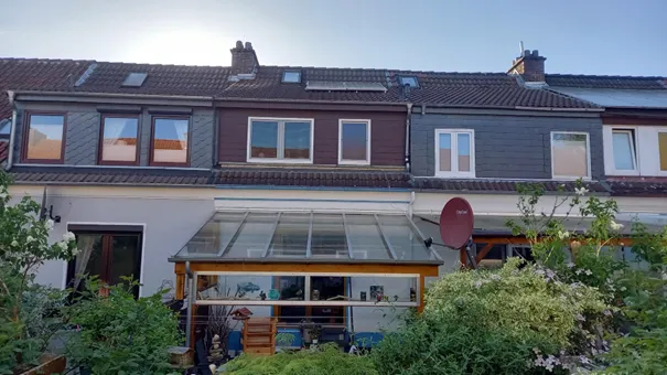 Außenansicht eines Reihen-Hauses mit Wintergarten und PV-Anlage auf dem Dach