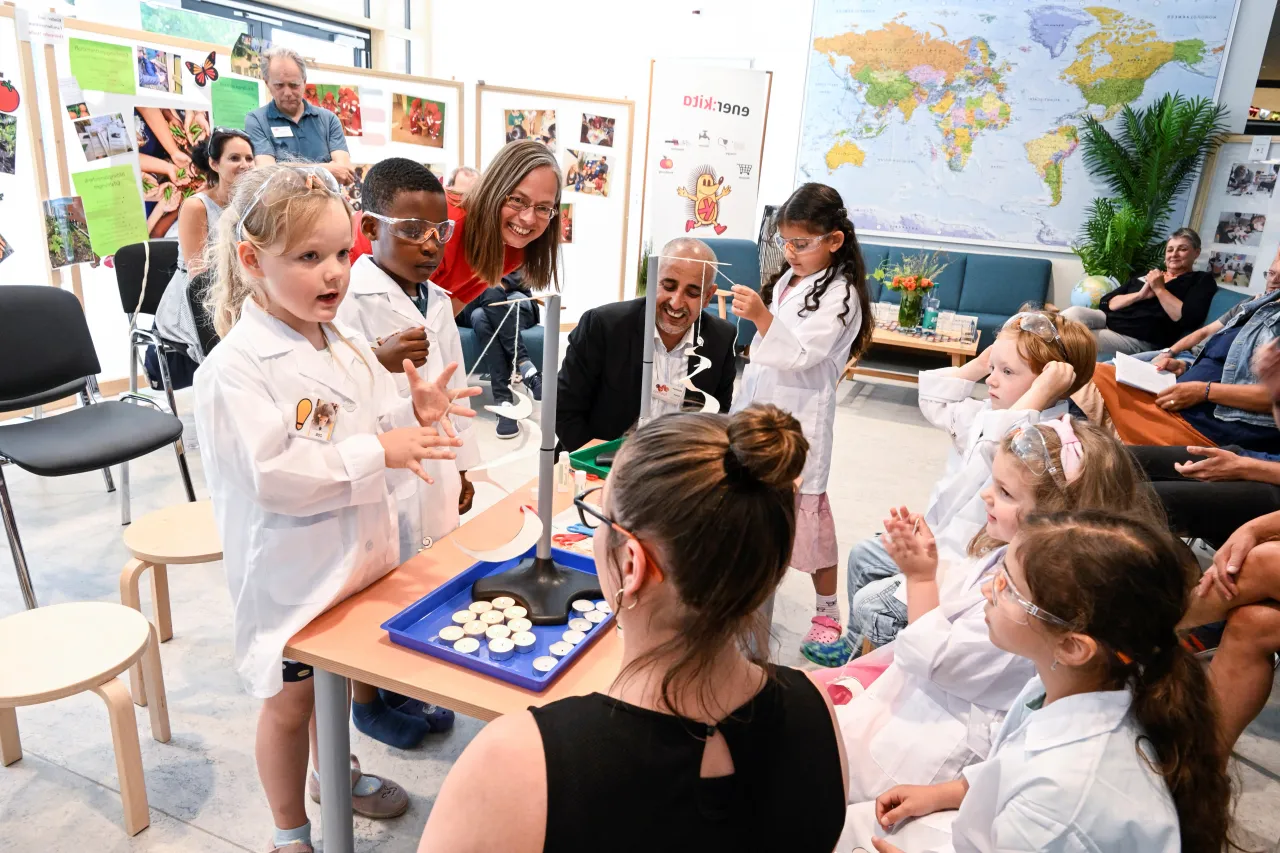 Kinder machen Experiment und tragen Kittel und Schutzbrillen
