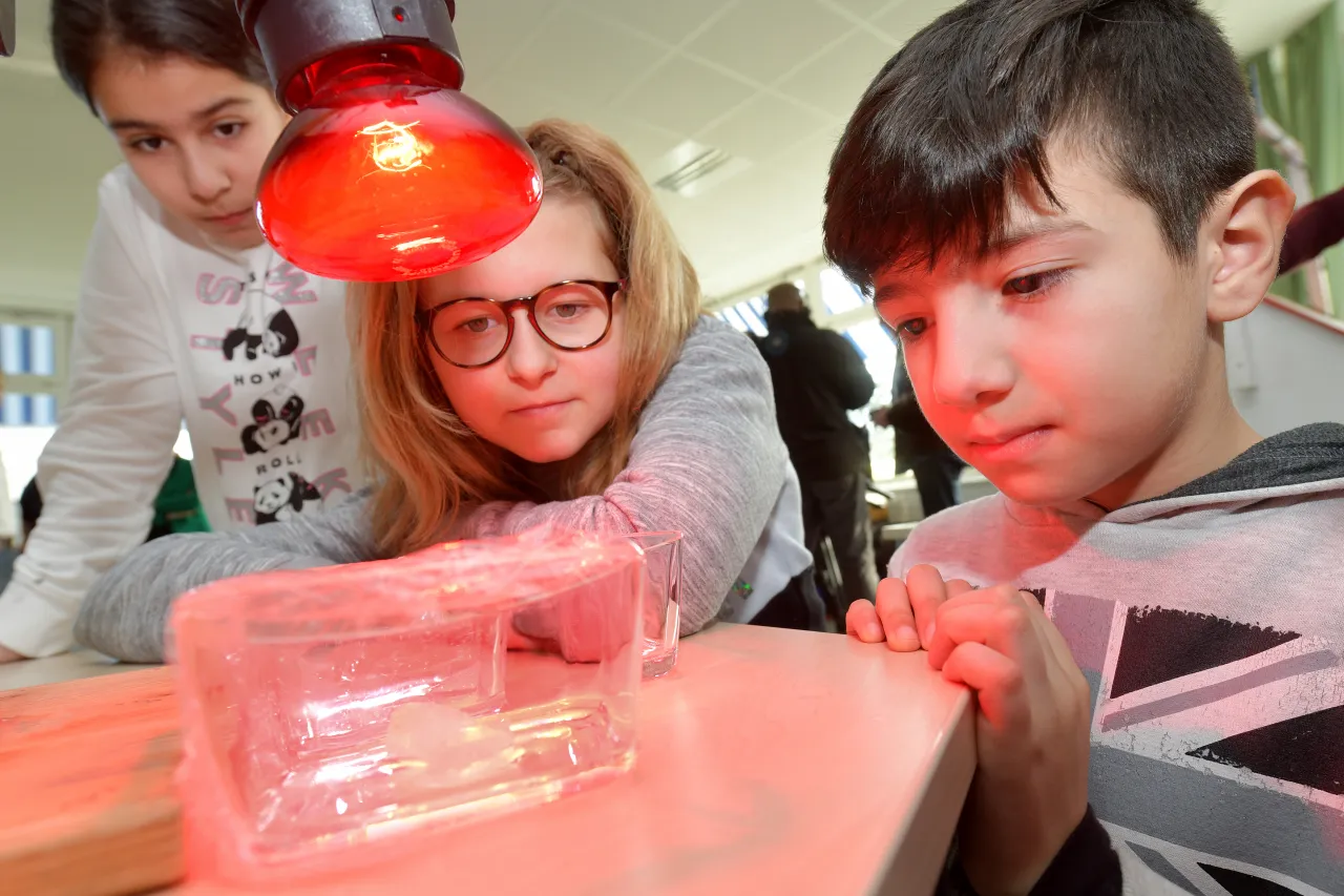 Schülerinnen und Schüler aus dem 4. Jahrgang beobachten den Treibhauseffekt beim Experimentieren.