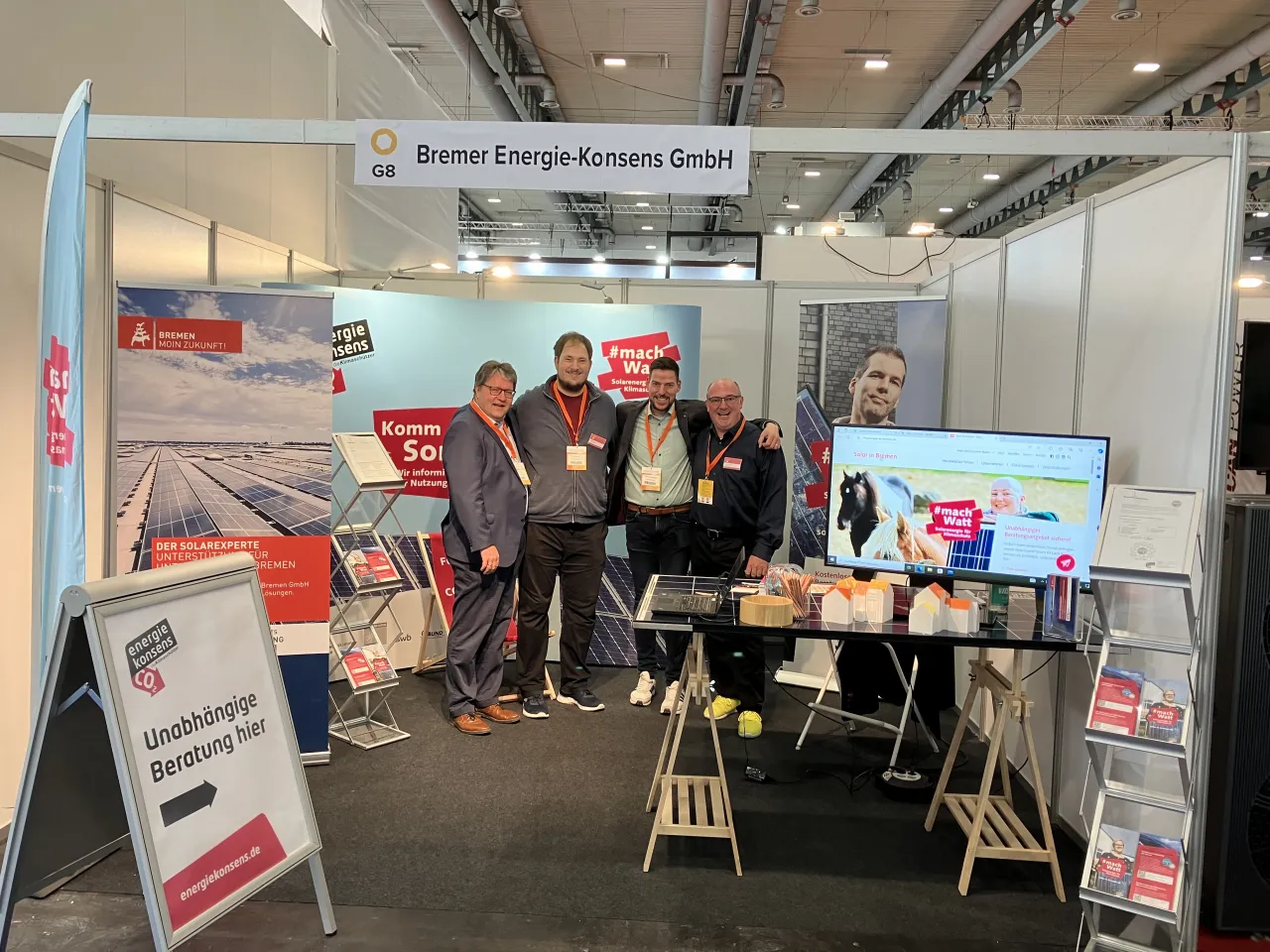 Gruppenbild: Vier Männer stehen auf dem Solar-Messestand von energiekonsens