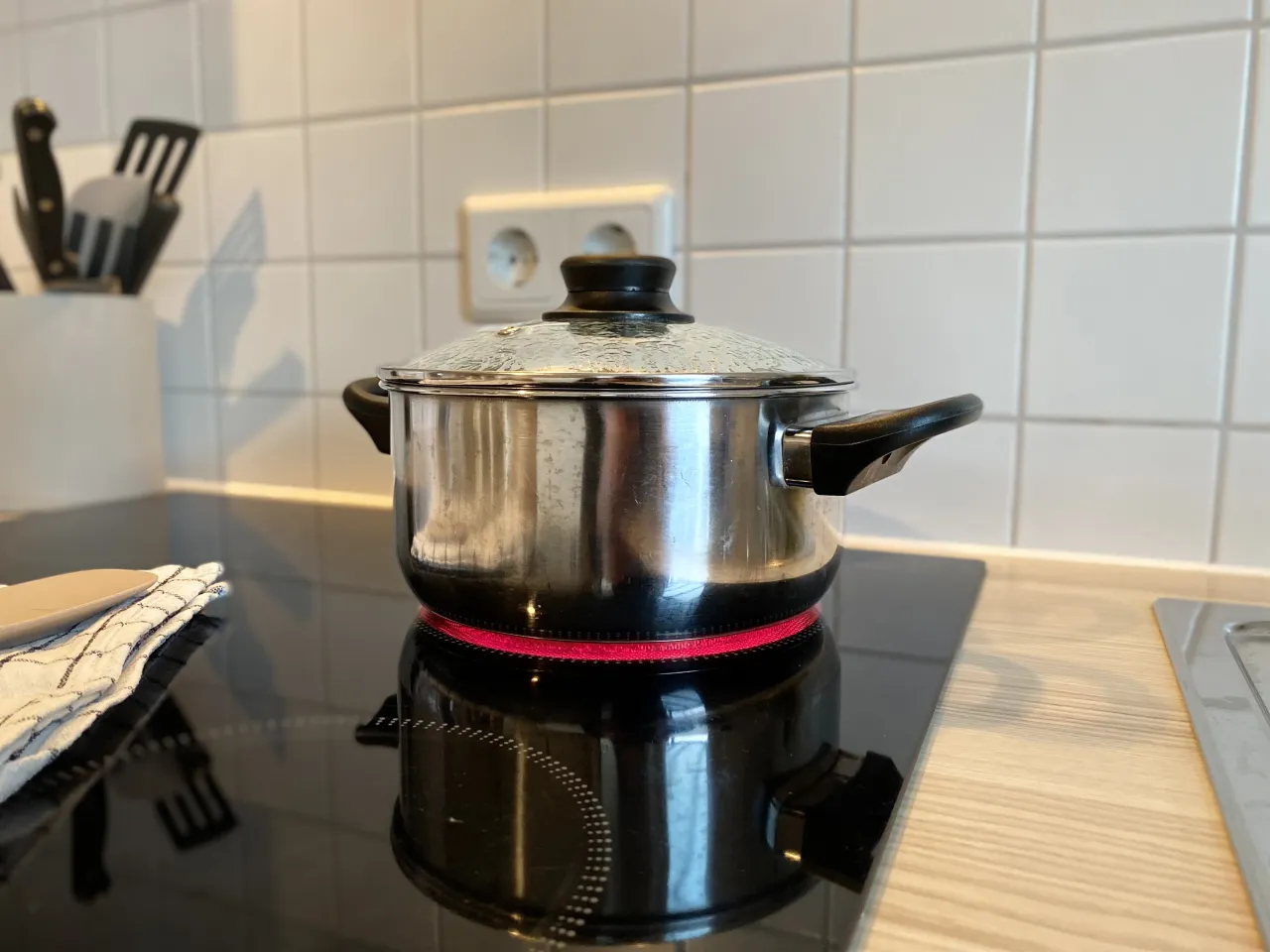 Kochtopf mit Deckel auf Herd, Herdplatte leuchtet rot