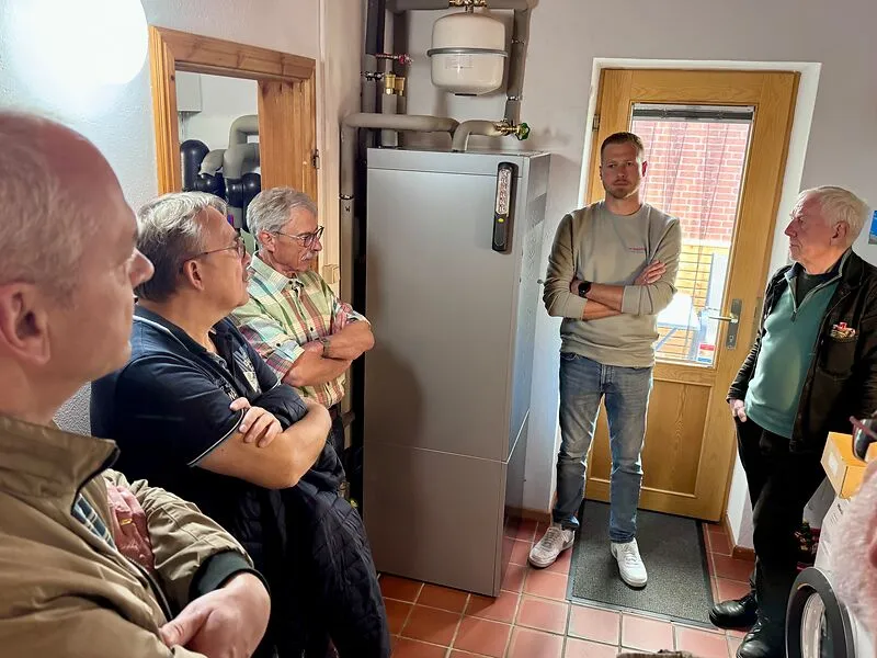 Fünf Männer stehen an dem Warmwasserspeicher einer Wärmepumpe