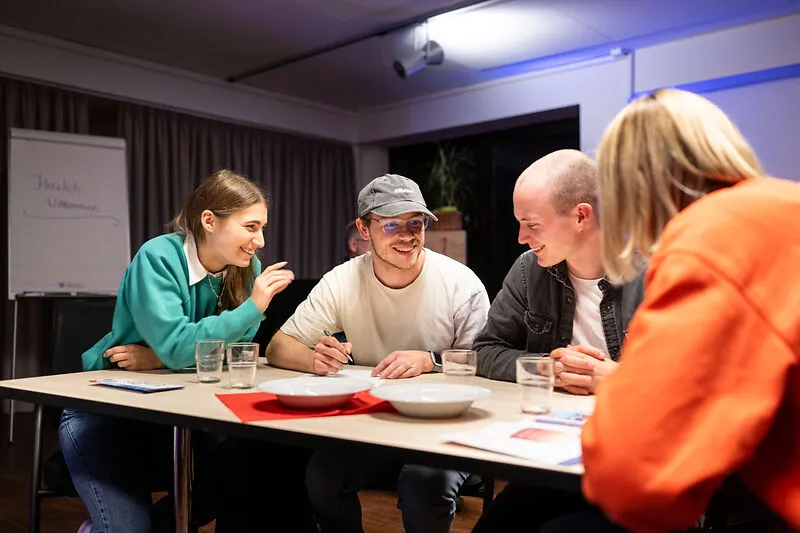 Vier Personen sitzen im Klima Bau Zentrum an einem Tisch und grübeln über die Quizfragen.