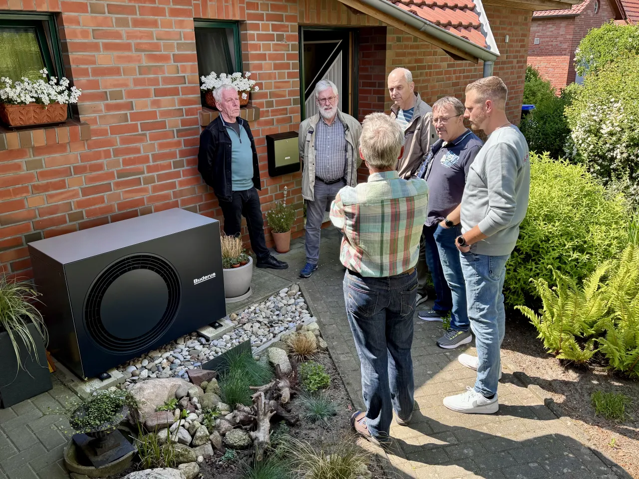 Sechs Männer stehen vor einem Einfamilienhaus an einer Wärmepumpe