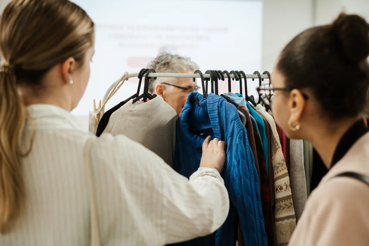 Zwei Frauen begutachten Kleider an einer Kleiderstange.