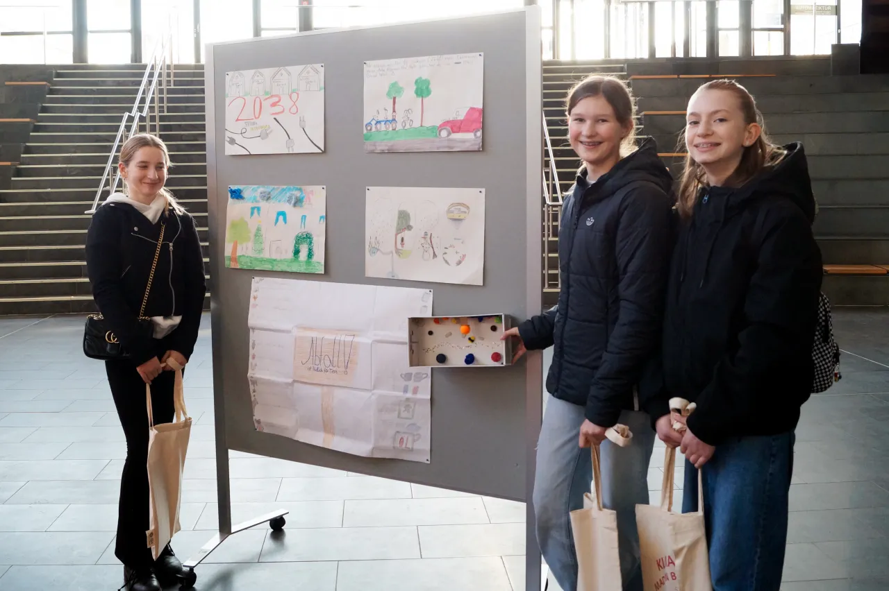 Drei Schülerinnen stehen vor einer Pinnwand mit ihren Kunstwerken