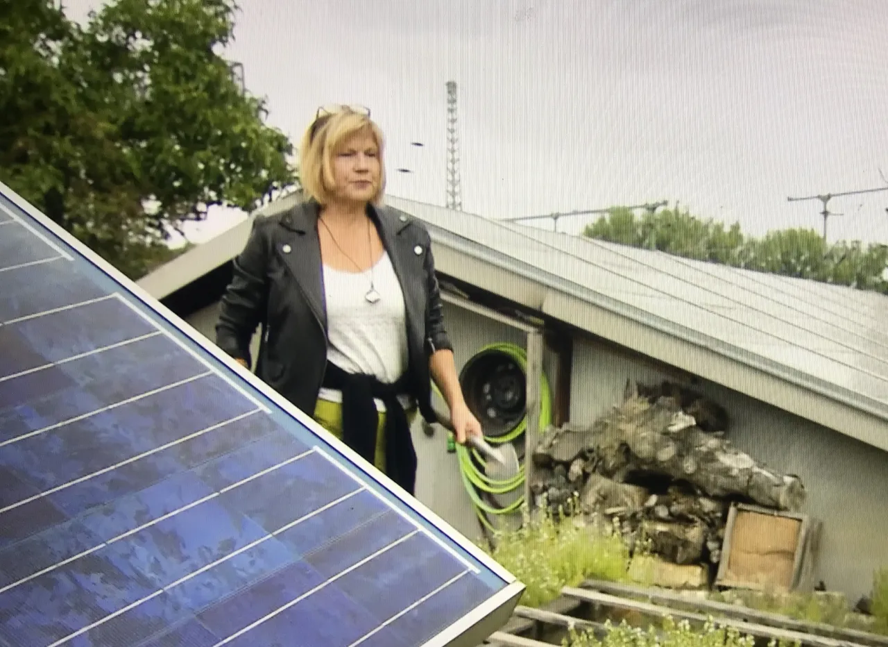 Frau steht hinter PV-Anlage.