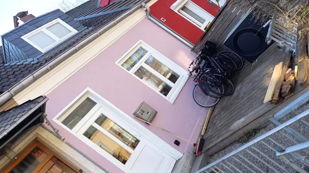 Violette und gedämmte Front eines einstöckigen Reihenhauses mit einer Wärmepumpe davor