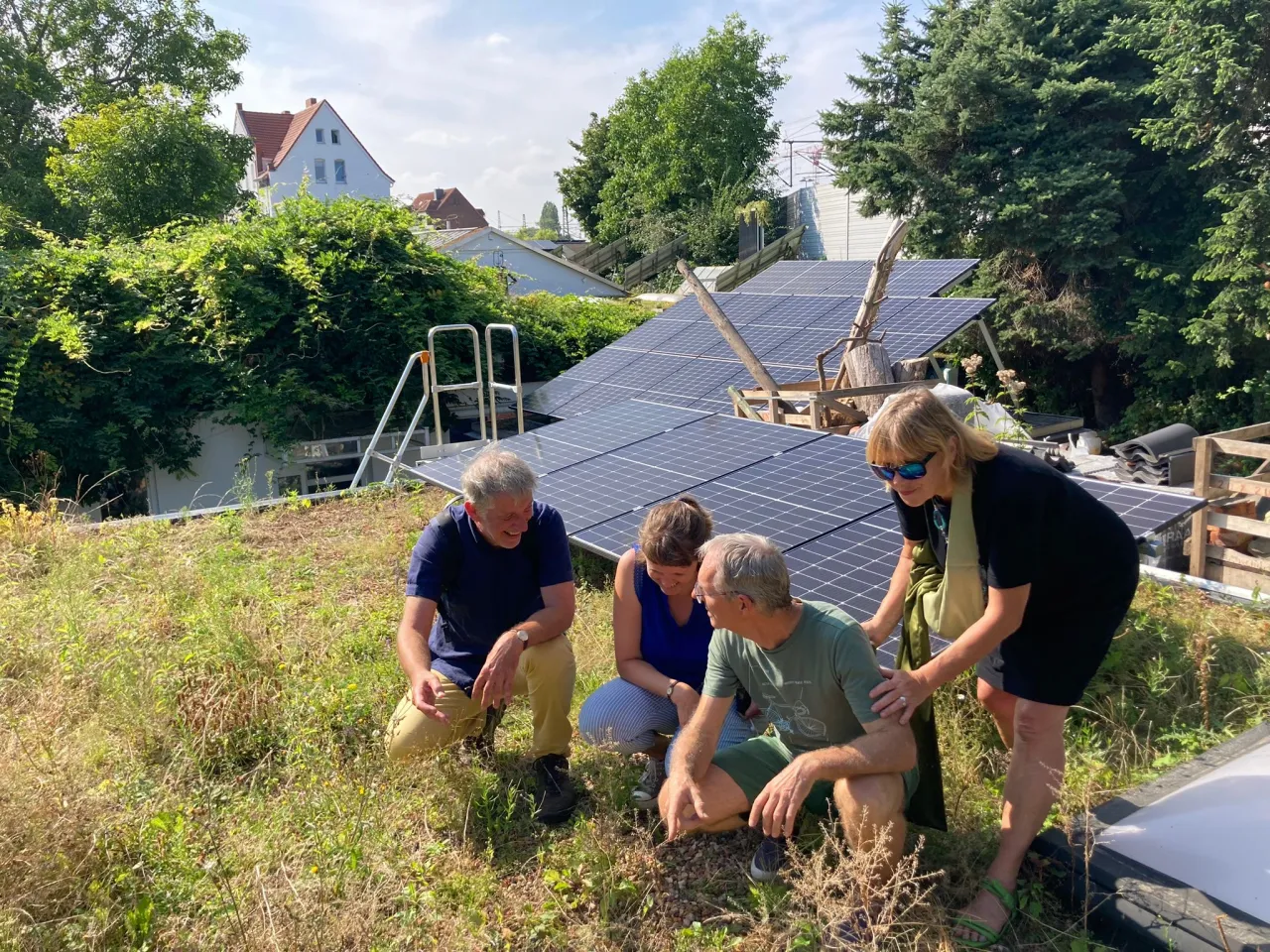 Eine Gruppe kniet vor einer Solaranlage auf einem Gr&uuml;ndach