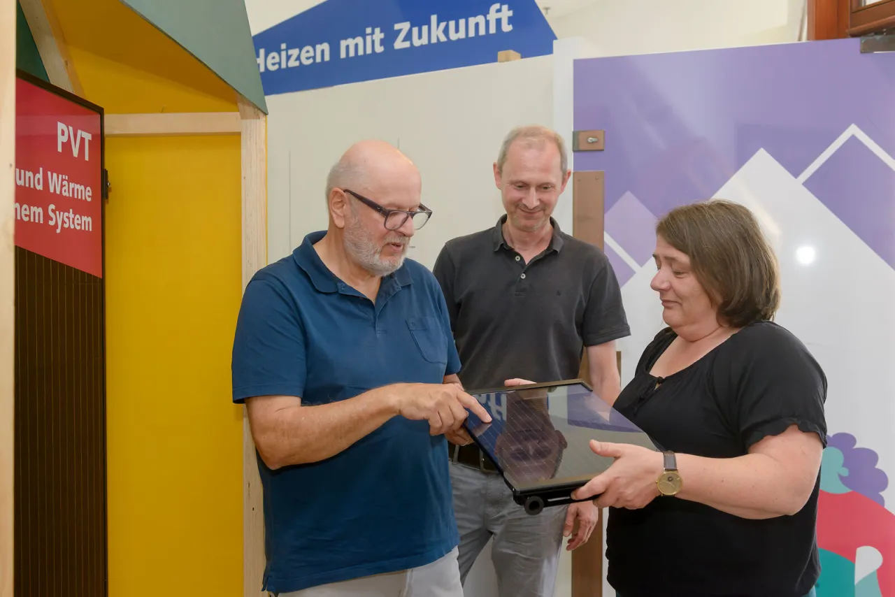 Drei Menschen schauen sich im Klima Bau Zentrum Bremerhaven einen PVT-Kollektor an.