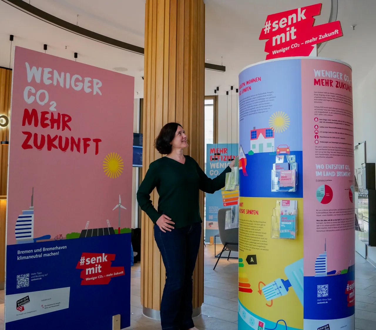 „Senatorin Kathrin Moosdorf begutachtet die Ausstellungssäule der Kampagne #senkmit: Weniger CO2 – mehr Zukunft.“