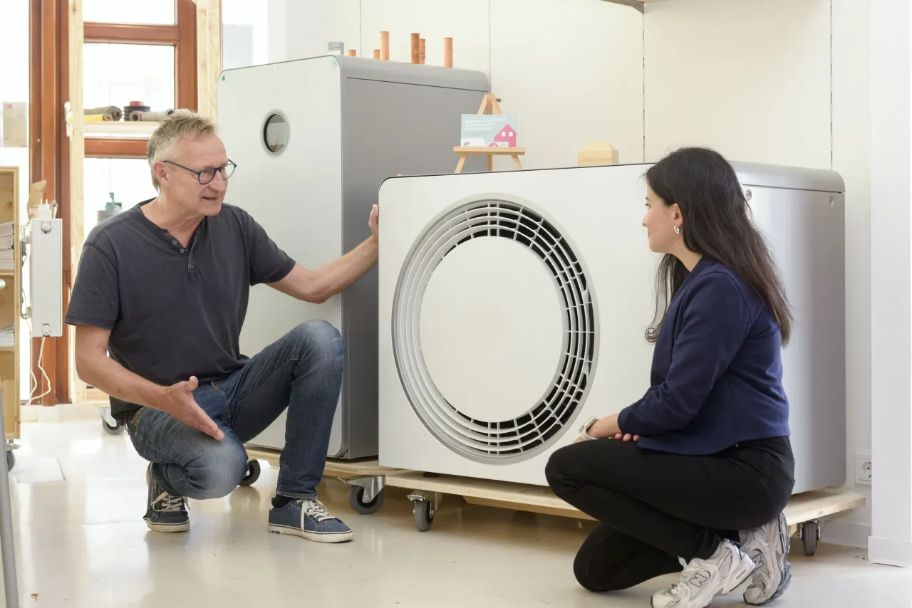 Mann und Frau in einer Beratungssituation vor einer Wärmepumpe.
