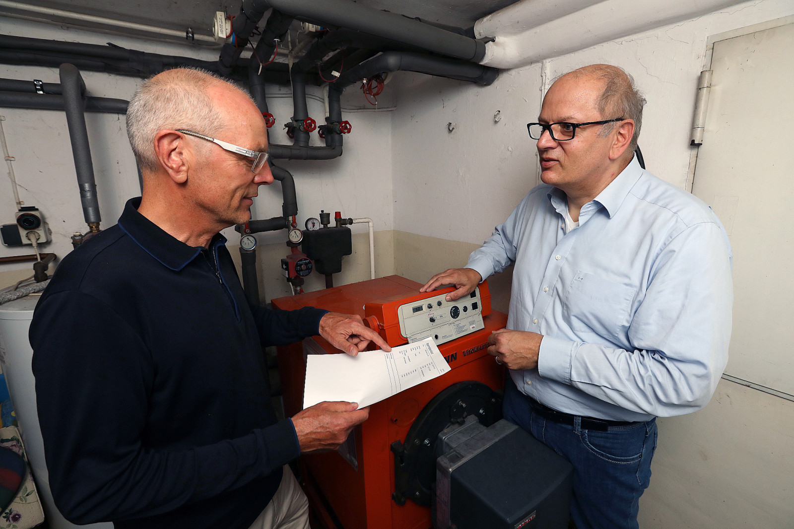 Heinfried Becker (energiekonsens) und Rainer Mathia (SKUMS) vor alter Ölheizung