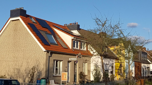 Die Außenansicht eines Reihenendhauses mit PV-Anlage auf dem Dach
