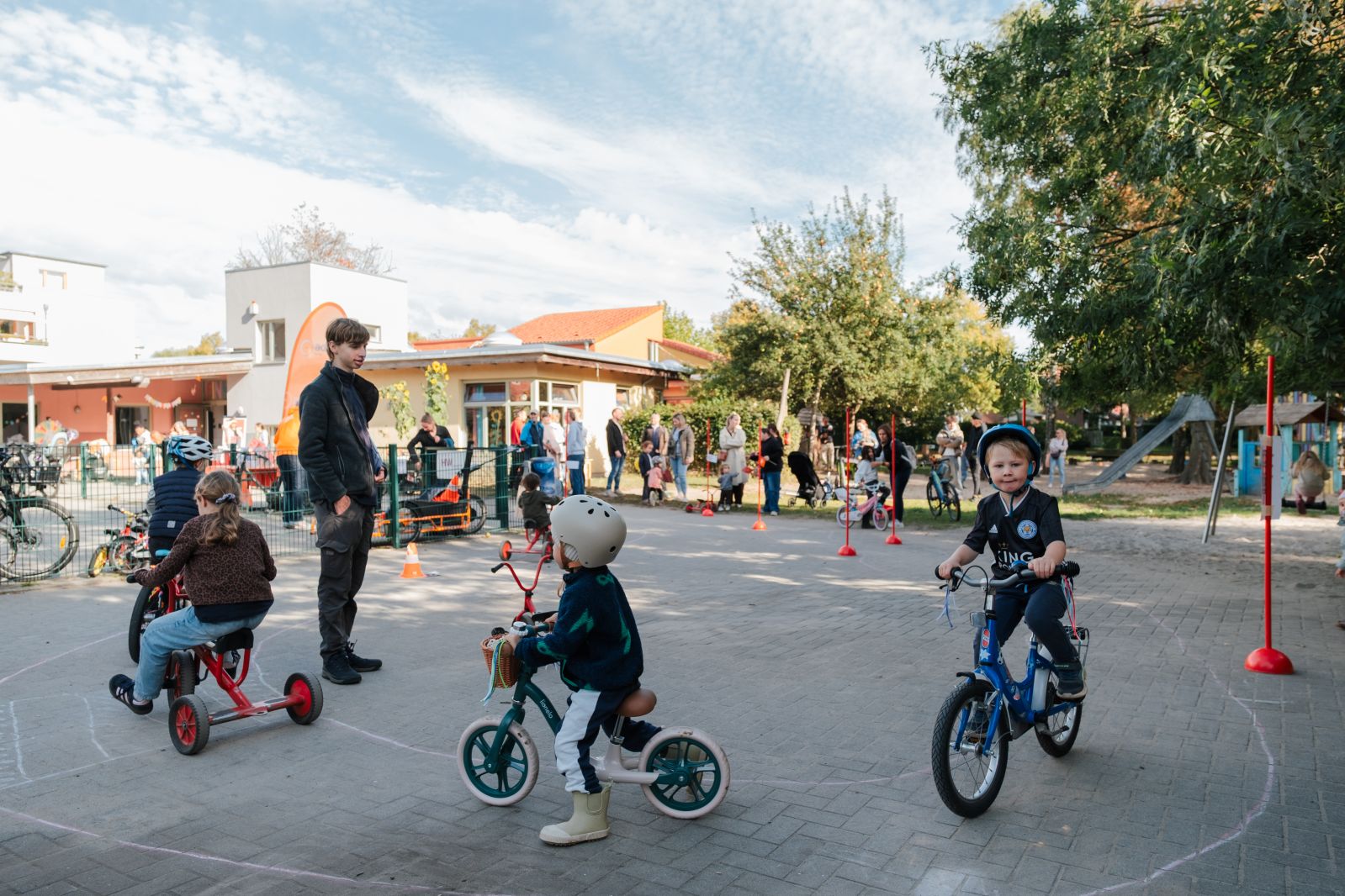Viele Kinder fahren mit Laufrädern und Fahrrädern durch einen Parkour
