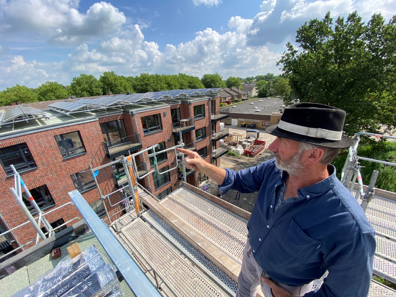 Bauleiter des Quartiers Seewenjestraße in Gröpelingen zeigt auf Dach mit PV-Anlagen