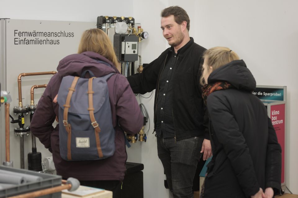 Berater von energiekonsens erklärt zwei Frauen Fernwärmeanschluss in Einfamilienhäusern