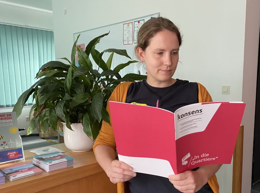 Jahresmagazin 2023: Kollegin steht mit aktuellem Heft in der Hand vor einer Pflanze