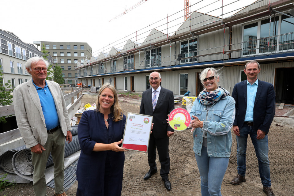 Senatorin Maike Schaefer zeichnet Ellener Hof als Klimaschutzsiedlung aus, Gruppenbild vor Baustelle