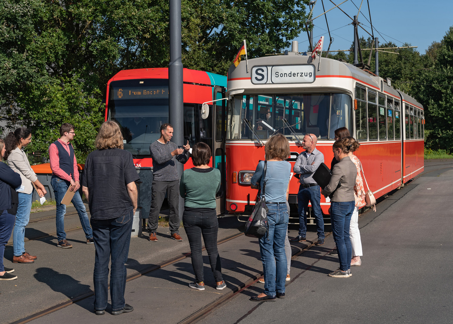Personen sprechen vor historischer Straßenbahn